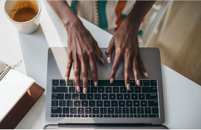 black woman's hands typing at keyboard